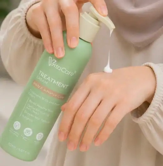 Botol semasa Vitacare dengan pam dan dasar penuh sedang mengeluarkan krim pada kulit tangan yang utuh