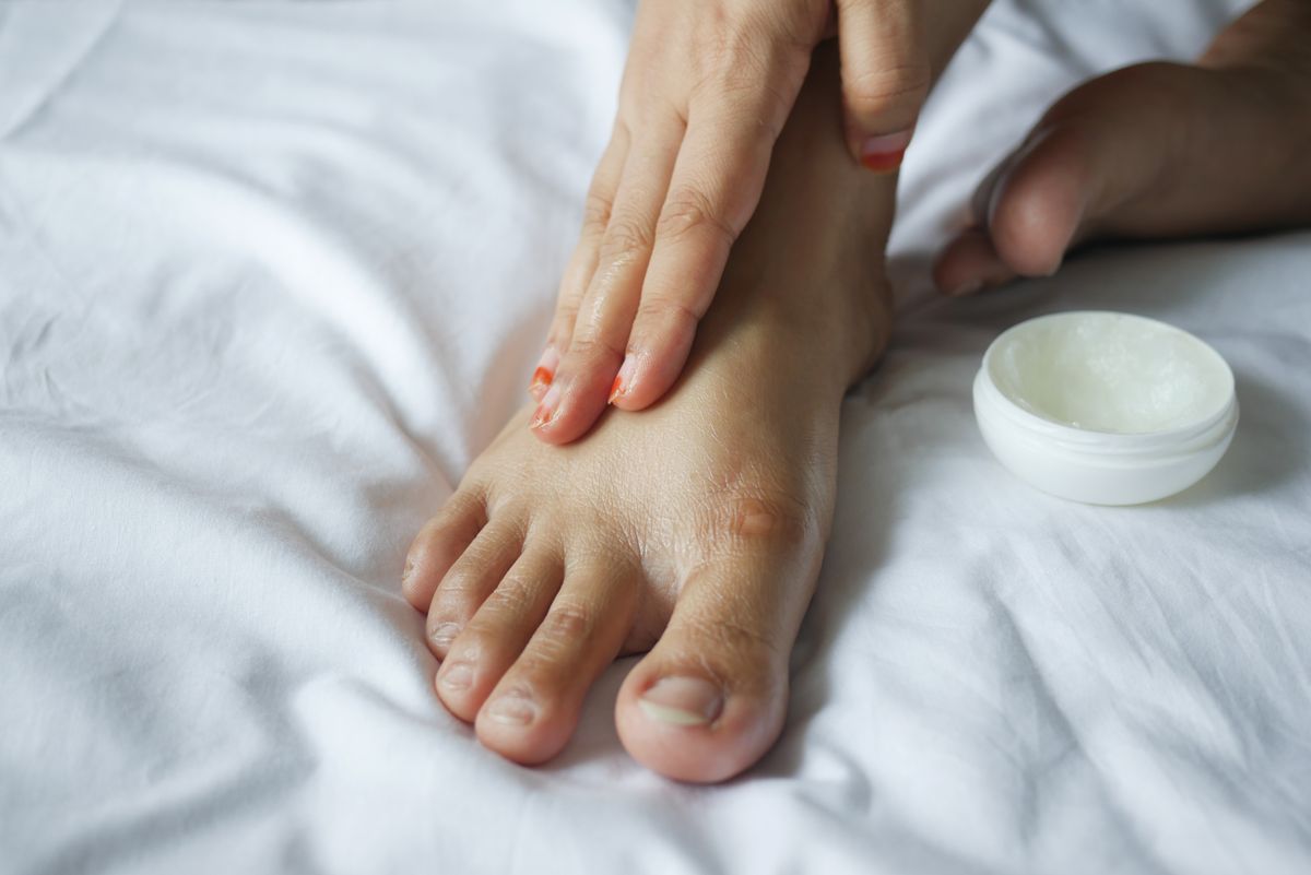 Tangan menyapu pelembap pada kulit kaki